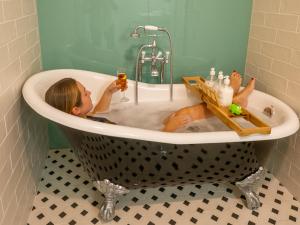 ein Kind, das mit einem Getränk in einer Badewanne sitzt in der Unterkunft Castelo Gerês - Exquisite Eco-Cottage - jacuzzi in Lindoso + 30 Fotos