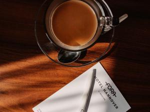 a cup of coffee sitting on a table with a note at Fora Hotel Hannover by Mercure in Hannover