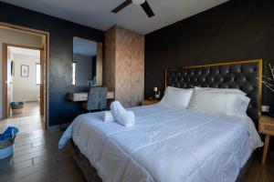 a bedroom with a large white bed with a black wall at Rosarito Getaway - Mangle Condos in Rosarito