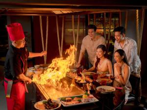 a group of people standing around a grill with fire at Grand Mercure Bangkok Atrium in Bangkok