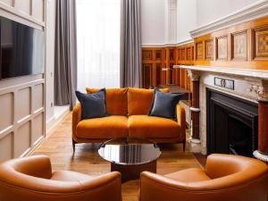 an orange couch and two chairs in a living room at The Municipal Hotel Liverpool - MGallery in Liverpool +128 photos