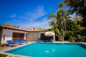 a villa with a swimming pool with chairs and an umbrella at Hotel Fundo El Arrabal in Ica