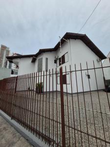 une clôture devant une maison blanche dans l'établissement Anexxo HC, à Palhoça