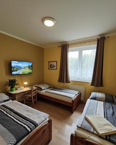 a bedroom with two beds and a tv on the wall at Penzion & Restaurace Kozabar in Luby