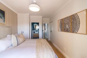 BRAND NEW Luxury Apartment with Ocean View في بليتنبيرغ باي: غرفة نوم بها سرير مع مقعد عليها