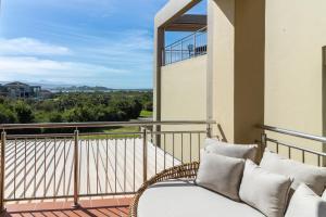 BRAND NEW Luxury Apartment with Ocean View في بليتنبيرغ باي: كرسي الخوص على شرفة مع منظر