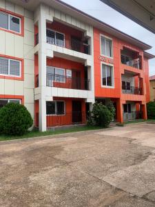 an orange and white apartment building with a parking lot at Cozy and Comfortable 2 bedroom for Families Home-away near Airport in Accra