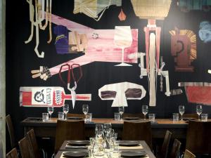a dining room with tables and a wall with a mural at Peppers Gallery Hotel in Canberra