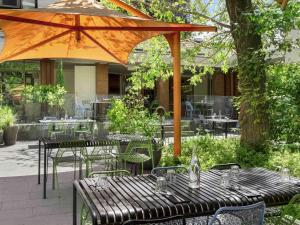 a patio with tables and chairs and an umbrella at Peppers Gallery Hotel in Canberra
