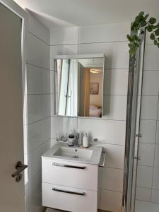 a white bathroom with a sink and a mirror at Mc Solutions Apartment im Zentrum in St. Gallen