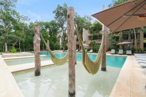 a pool with two hammocks and an umbrella at Stylish 1BR Condo with Private Pool & Balcony in Tulum