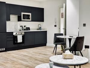 Una cocina con gabinetes negros y una mesa y sillas. en Royal Stay-Leeds City centre Apartment, en Central Station 1 foto más