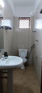 a bathroom with a white sink and a toilet at Ilao Homes- Studio Apartment in Kilifi
