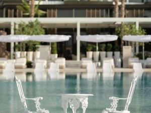 un grupo de sillas y mesas blancas en una piscina en Delano Dubai at Bluewaters, en Dubái