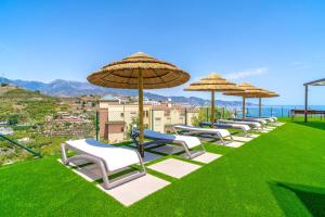a row of lawn chairs with umbrellas and the ocean at Bayview Hills Suite by Casasol in Torrox