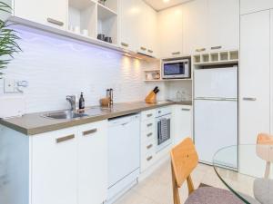 a white kitchen with a sink and a refrigerator at Cozy City Apt with Pool, Gym & View by Zodiak Stays in Auckland