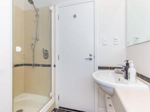 a white bathroom with a shower and a sink at Cozy City Apt with Pool, Gym & View by Zodiak Stays in Auckland +8 photos