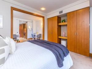 Un dormitorio con una gran cama blanca y armarios de madera. en Cozy Central Apt with Pool & Gym by Zodiak Stays, en Auckland 19 fotos más