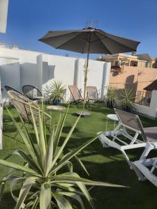 a patio with chairs and an umbrella and a plant at Cala Azul-few steps from the beach in La Cala de Mijas