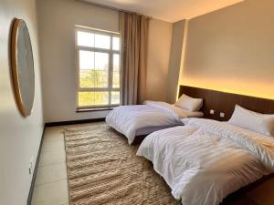 two beds in a room with a large window at تالية مارينا هاوس غرفتين TALIA MARINA FAMILIES PROFESSIONALs in King Abdullah Economic City +27 photos