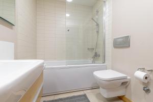 a bathroom with a white tub and a toilet and a sink at Panorama Sky Apartment near Riga Airport & City Center in Rīga +30 photos