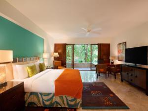 a bedroom with a bed and a desk and a television at Fairmont Mayakoba in Playa del Carmen