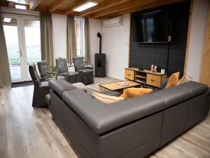 een woonkamer met een bank en een tv bij Tiny Home in Oirschot next to forest in Haghorst