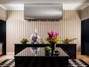 a chef standing in a kitchen preparing food at Pullman Chennai Anna Salai - Premium Brand By Accor in Chennai