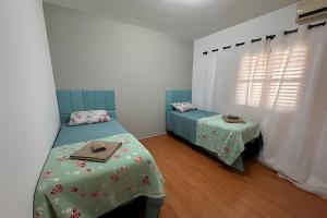 a bedroom with two twin beds and a window at Casa Refúgio Verde – Conforto em SJBVista in São João da Boa Vista
