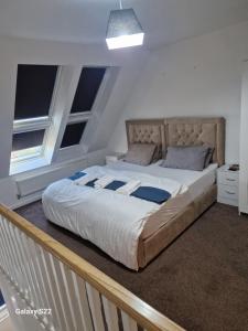 a large bed in a bedroom with two windows at Blue Haven 2 in Manchester
