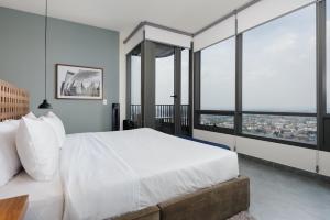 a bedroom with a large white bed and large windows at Be Grand by Wynwood House in Mexico City