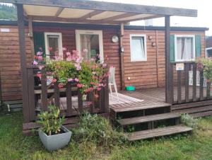 a cabin with a deck with flowers on it at Mobilhomme munster in Munster