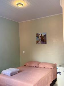 a bedroom with a bed with pink sheets and a picture on the wall at pousada j&m in São Luís +1 photo
