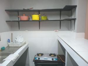 uma cozinha com um fogão, um lavatório e prateleiras em The Truenorth apartments chitiri em Ukunda