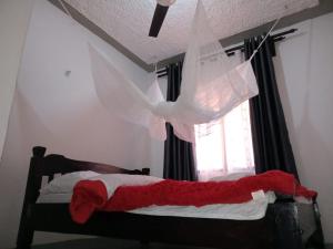 um quarto com uma cama com um cobertor vermelho e uma janela em The Truenorth apartments chitiri em Ukunda