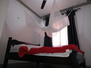 um quarto com uma cama com um cobertor vermelho e uma janela em The Truenorth apartments chitiri em Ukunda