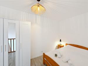ein weißes Schlafzimmer mit einem Bett und einem Kronleuchter in der Unterkunft Le Roazhon Park - Balcon & Garage Privé - Duplex in Rennes