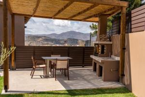 a patio with a table and chairs and a view of the mountains at Luxury Suites with BBQ next to Heraklion by Kalles Homes & Suites in Áno Kalésia