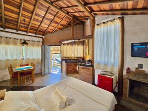 a bedroom with a bed and a kitchen with a table at Chalezinho Mata Virgem - perto do centro e cachoeiras, cozinha completa e churrasqueira in Carrancas