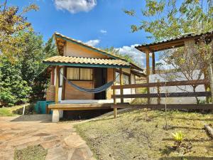 a small house with a hammock in front of it at Chalezinho Mata Virgem - perto do centro e cachoeiras, cozinha completa e churrasqueira in Carrancas