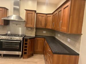 a kitchen with wooden cabinets and a stove top oven at Dairy House in Oldham