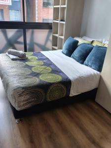 a bed with blue pillows on it in a room at Hermoso Apartaestudio LOFT in Bogotá