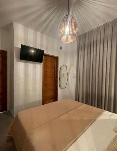 a bedroom with a bed and a tv on the wall at Maré Mansa Suítes Icaraizinho in Amontada