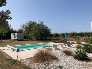 a swimming pool with tables and chairs and a trailer at Les Volets Bleus in Bernay
