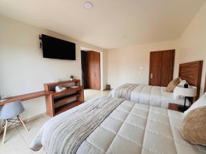 a hotel room with two beds and a television at Quinta Candela Hotel in Chignahuapan