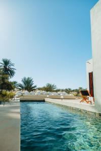 einen Pool in einem Resort mit Stühlen und einem Gebäude in der Unterkunft Pal Maya in Tozeur