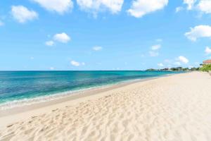 a sandy beach with the ocean in the background at The Sands #1 - New 7Mile Beach Condo with Rooftop Pool & Luxe Interiors in West Bay