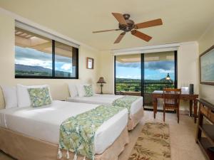 Un dormitorio con dos camas y un escritorio y ventanas. en Polo Beach Club 801, en Wailea