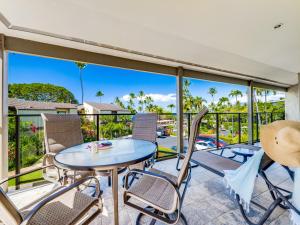 Un patio con una mesa y sillas en un balcón. en Wailea Elua Village 910, en Wailea