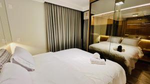 een hotelkamer met twee bedden en een spiegel bij Flat Luxo Jardins com Piscina, Vaga e serviços in Sao Paulo +27 foto's